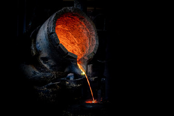 Foundry production. A ladle with molten metal. Pouring hot liquid metal into special molds. Close-up