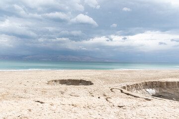 Sinkhole filled with turquoise water, near Dead Sea coastline. Hole formed when underground salt is dissolved by freshwater intrusion, due to continuing sea-level drop. . High quality photo
