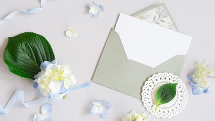 Top view of envelope and template for text, flowers and ribbons nearby