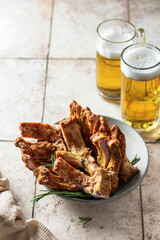 Smoked pork ribs with rosemary, beer and napkin on pink tile background