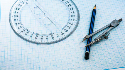 On blue graph paper are compasses, protractor, ruler, and a pencil
