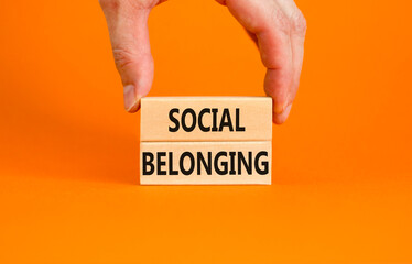 Social belonging symbol. Wooden blocks with concept words Social belonging on beautiful orange background. Businessman hand. Business political social belonging concept. Copy space.