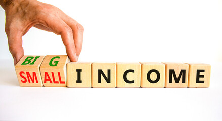 Big or small income symbol. Businessman turns wooden cubes and changes words Small income to Big income. Beautiful white table white background, copy space. Business big or small income concept.