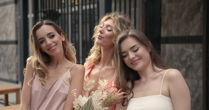 Three hapy ladies with bouquets posing in the city