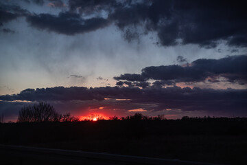 Fototapeta Piękny zachód słońca na zachmurzonym niebie z drzewami na horyzoncie	
 obraz