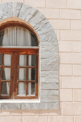 A window with stone arch. A beige brick wall background.