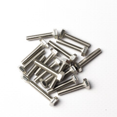A handful of bolts with shiny metal threads on a white background top view