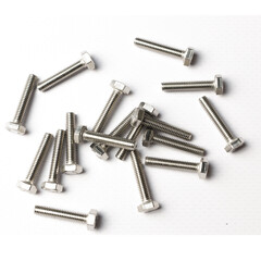 A handful of bolts are scattered across the table with a carving of shiny metal on a white background view from above