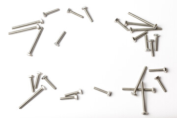 Many bolts are scattered on a table with a carving of shiny metal on a white background view from above in the center an empty space for inscription