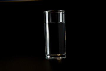 A clean glass glass glass with water on a black background. Side view