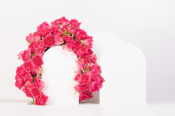 Delicate summer pink spray roses as framing of arch with two podiums on white abstract scene mockup. Template floral showcase for presentation of cosmetic, goods, advertising, design, card, poster.