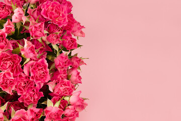 Delicate pink little spray roses as border on soft light pastel pink background, texture, copy space, top view. Spring flowers texture for advertising, poster, card, flyer.