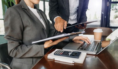 Business documents on office desk with tablet, graph and two colleagues discussing data working .