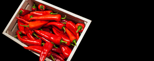 Spicy Chillli red peppers in wooden box on black background concept banner