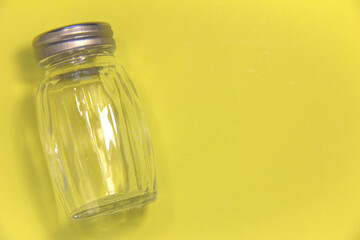 Empty salt shaker. On a yellow background. Place for text.