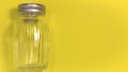 Empty salt shaker. On a yellow background. Place for text.