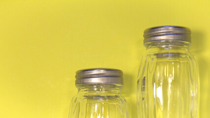 Empty salt shakers. On a yellow background. Place for text.