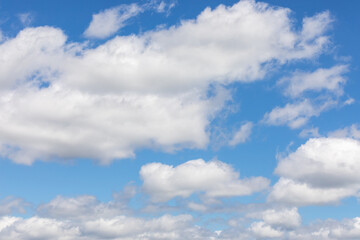 Naklejka na ściany i meble Disheveled snow-white clouds against background of clear blue summer sky