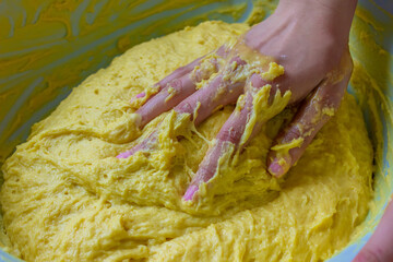 the girl kneads the dough in a bowl.
