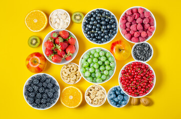 Berries, fruits and nuts on a yellow background. Vegetarian food. Copy space