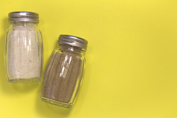 Salt and pepper in salt shakers. On a yellow background. Place for text.