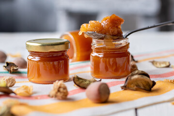 apple jam in a spoon on a jar. fabric light background. marmalade orange pear