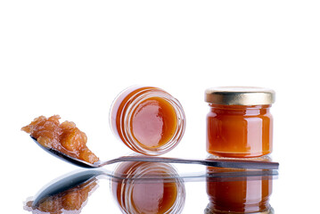 jam in a jar and a spoon. apple and pear jam in a spoon on a white isolated mirror background
