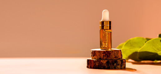 Cosmetic glass dropper bottle on wooden podium with oil, serum or fruit peeling in the sunlight....