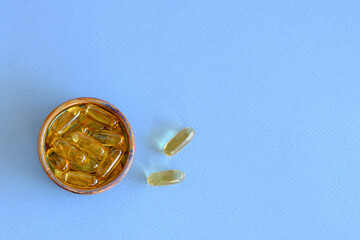 Top view closeup of an omega 3 oil capsule in a small bowl.