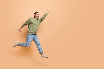 Full length profile photo of energetic excited man raise hand look empty space isolated on beige...