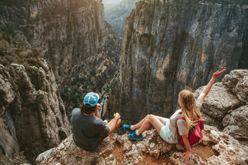 Couple hiking together sitting on cliff edge travel healthy lifestyle active vacations outdoor man...