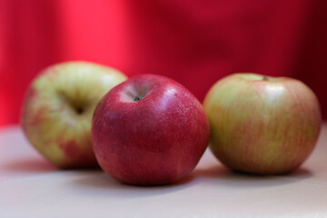 Red apples are lying on a white table