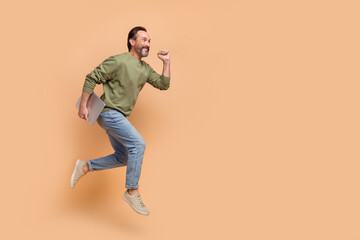 Full body photo of excited sporty man look empty space hurry rush isolated on beige color background