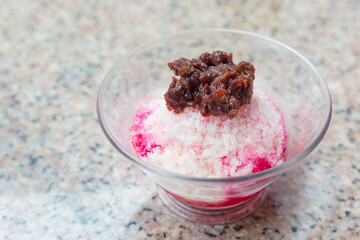 Traditional Japanese Dessert , A Bowl of Red Bean Sweet with red ice was on top with condensed milk and put on a granite table.