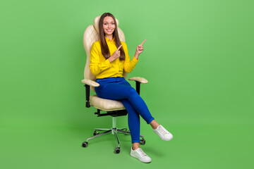 Full length body size view of attractive cheery girl sitting in chair showing copy space isolated...