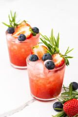 Refreshing drink with strawberry smoothie, summer sweet fruit juice with blueberries and rosemary