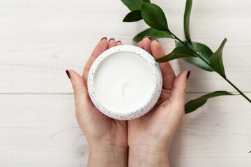 Female hands holding scented candle, top view.