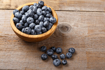 Freshly picked blueberries in a wooden bowl. Healthy food and nutrition concept.