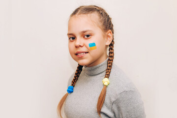 Close-up portrait of a girl, a blue-yellow drawing of the flag of Ukraine is drawn on her cheek.