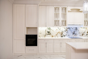 interior of a white kitchen made of natural wood with built-in appliances and lighting