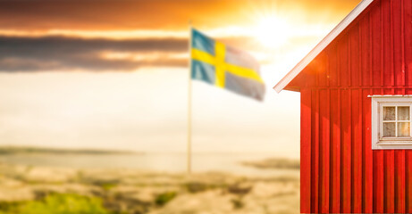 Rotes Schwedenhaus mit Schwedischer Flagge mit Sonnenlicht
