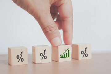 hand holding increasing graph with blurred rising percent icon on wooden cube block for business...