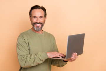 Portrait of attractive cheerful successful skilled man using laptop web surfing isolated over beige pastel color background