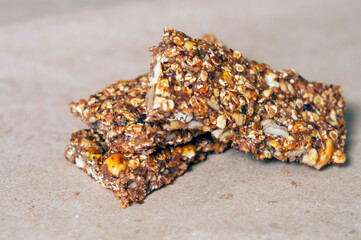sweet bar with muesli, dried fruits and nuts on craft paper close-up.