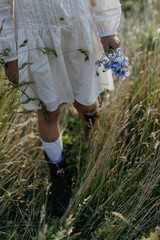 Little girl with blue flowers in the field.