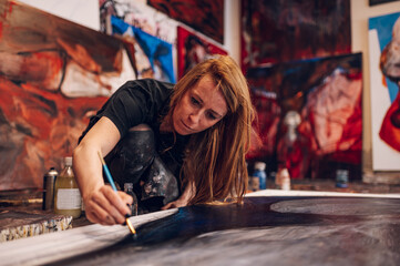 Naklejka na ściany i meble Female painter artist painting and creating her art in a creative studio