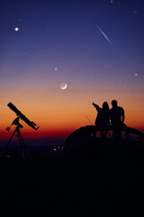 Couple stargazing together with a astronomical telescope.