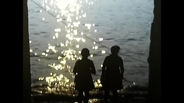 silhouettes of women by the lake at sunset 70s