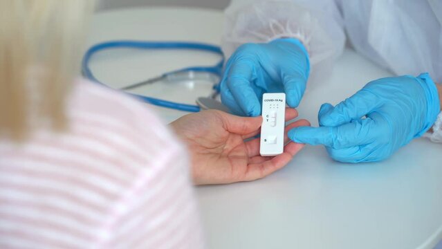Doctor gives rapid results of research antigen test for covid-19 to female patient in clinic. Quick swab method to coronavirus test.