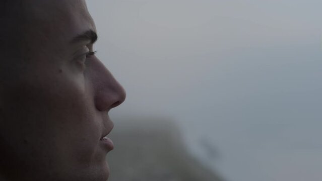 Dreamy man enjoying ocean landscape at sunrise. Calm guy talking with himself